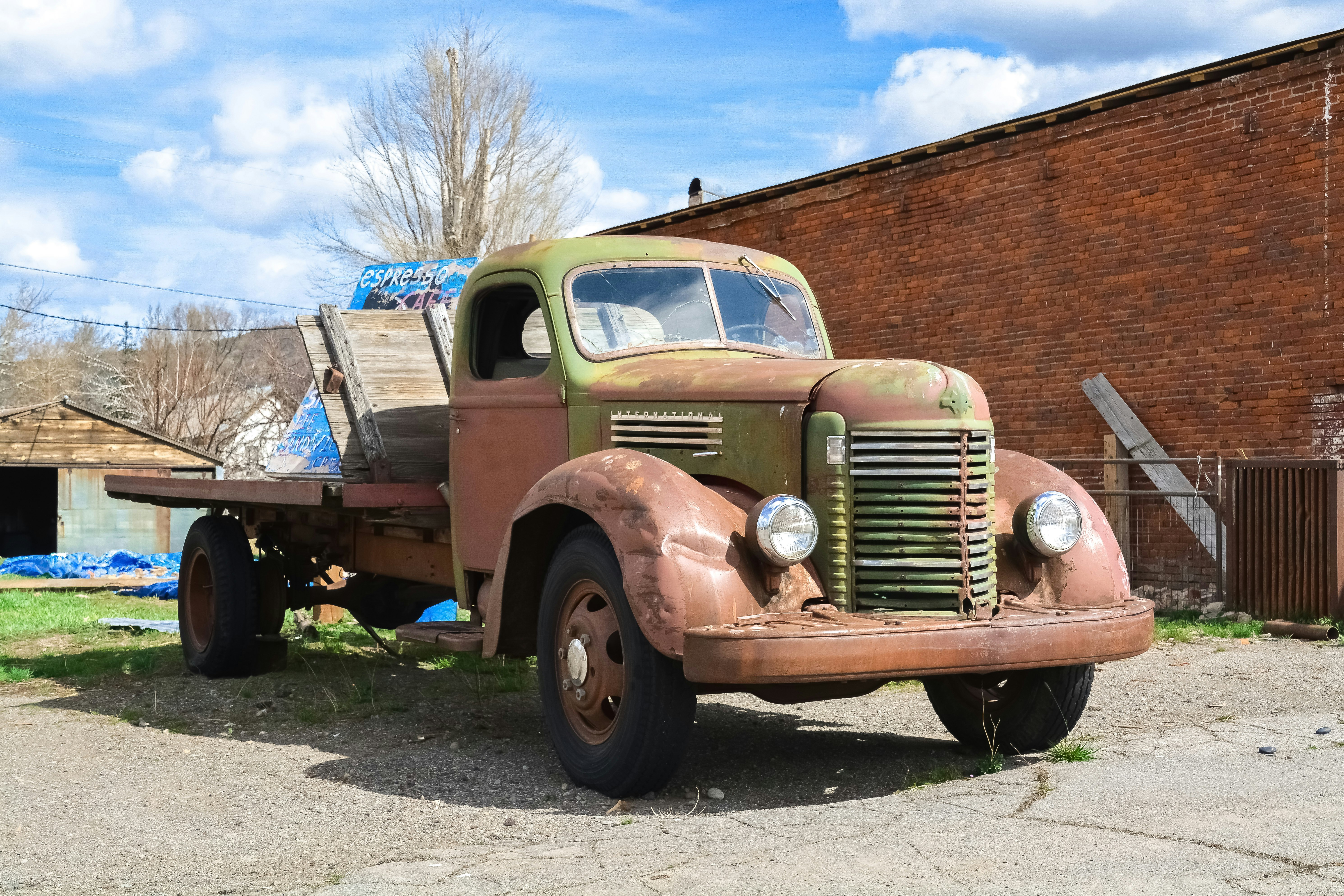 brown and white vintage truck parked beside brown bare tree during daytime